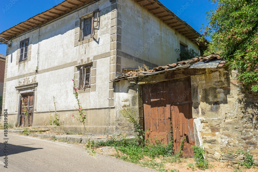 Fototapeta premium Old building with wooden doors and overgrown vegetation.