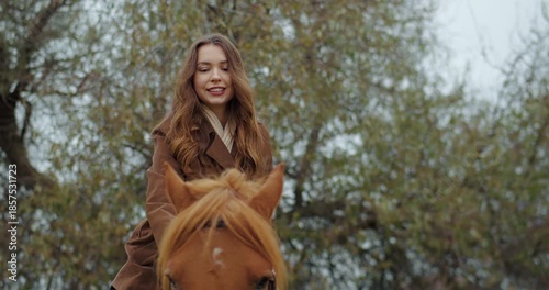 Young woman gently riding horse in nature