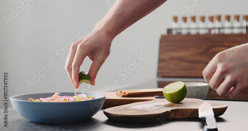 Man squeeze lime into greek salad in blue bowl