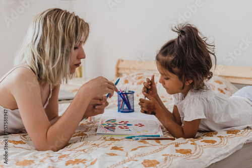 Mother and daughter drawing together on bed