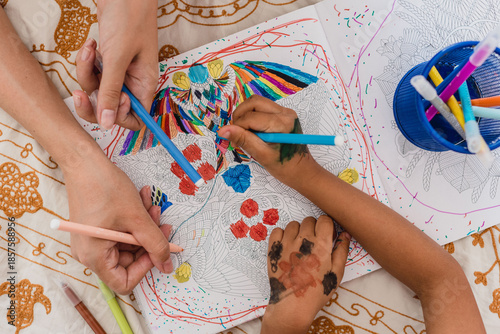 High view of mom and daughter painting with markers on the bed