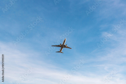 Passenger airplane flying high in clear blue sky viewed from below, minimalistic composition with large copyspace, concept of air travel, freedom, transportation, aviation and journey