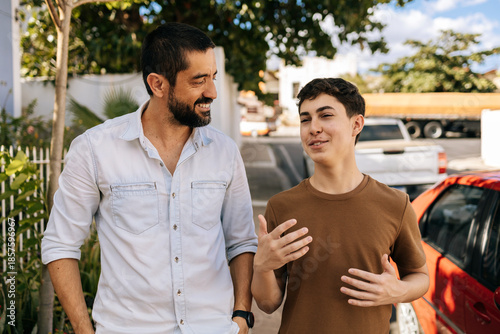 Teenage son speaks while his father listens attentively during an outdoor walk, highlighting active listening, empathy, guidance, emotional awareness, and family wellbeing