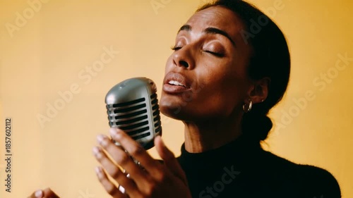 Expressive close up of soulful female singer performing into vintage microphone against warm background providing emotional concert style footage for music videos inspirational campaigns.