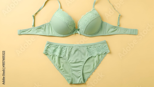 Light green lace bra and matching panties set displayed on a soft yellow background.