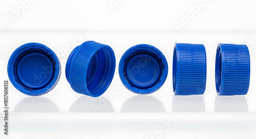 Five blue plastic bottle caps arranged in a row on a white background image