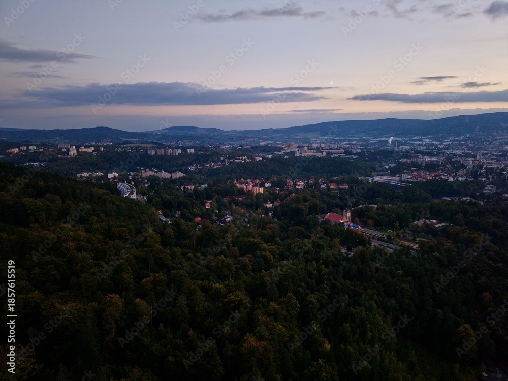 Obraz premium Transition From Daylight To Twilight With Silhouettes Blending Into Illuminated City Background