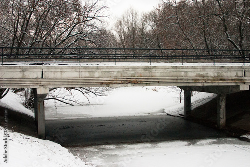 Bridge over the river in the city park under the snow in winter