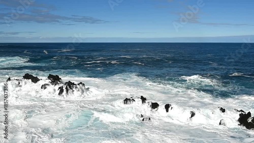 Waves of the blue Atlantic Ocean crashing into rocks on the coast. Porto Moniz, Madeira, Portugal