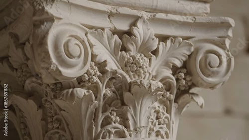Ornate white marble column capital with intricate carvings and floral motifs.