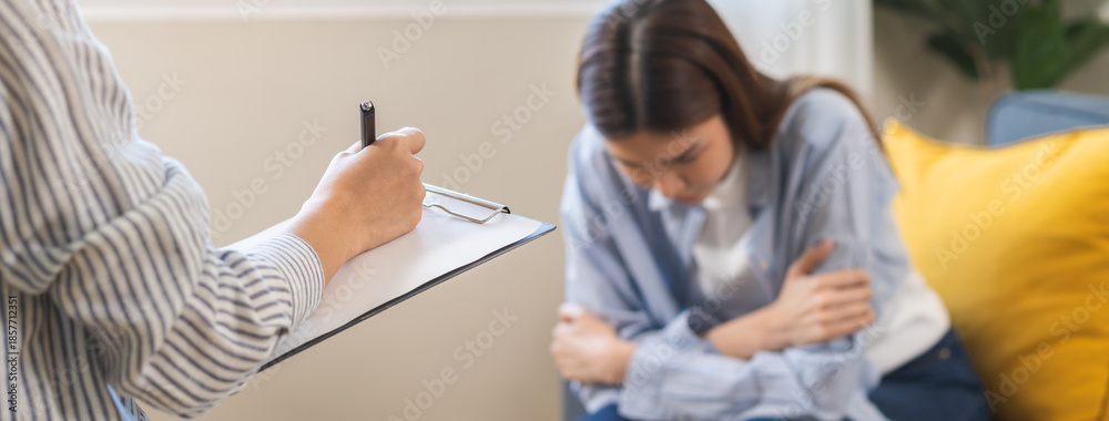 Obraz premium Psychology, depression. Suffer asian young woman consultation with psychologist while patient counseling mental therapy, doctor hand taking notes at clinic. Psychologist with sick mental health person