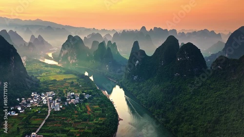 Aerial shot of spectacular karst mountain peaks and winding river with rural village at sunrise in Guilin, China. 