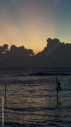 Traditional Sri Lankan stilt fisherman sitting on a pole in the indian ocean during a beautiful sunset, embodying a timeless and cultural fishing method against a scenic, tranquil backdrop