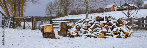 Winter landscape of a Ukrainian village with firewood for heating. Wood as a solid fuel. Concept: collecting firewood for heating a room for the winter.