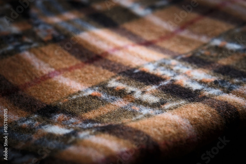 Macro close-up of brown plaid fabric showing woven texture and intersecting lines. Textile pattern, softness, and material detail