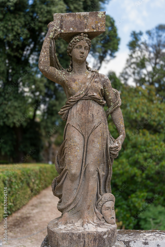 Fototapeta premium Italy - Caprarola - Palazzo Farnese - Marble statue of a caryatid in the formal gardens with lush greenery