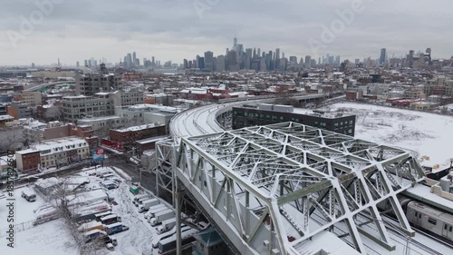 snowy winter elevated subway in Brooklyn heads towards NYC skylline
