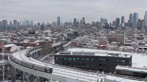 snowy winter elevated subway in Brooklyn heads away from NYC skylline