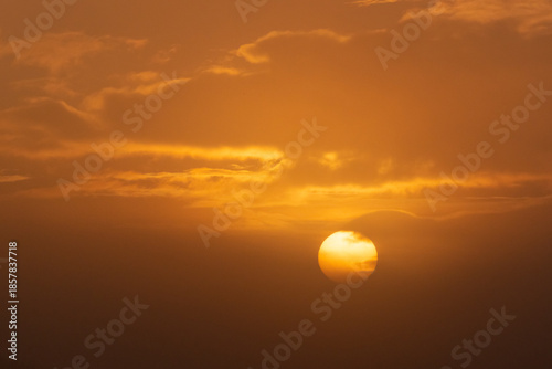 Sun emerging from behind thick fog and cloud as it rises on a winter morning