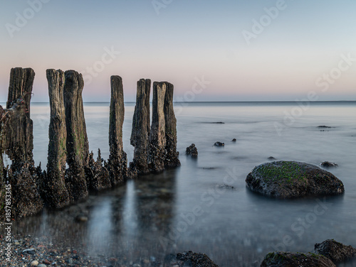Stones and planks on the beach washed by water