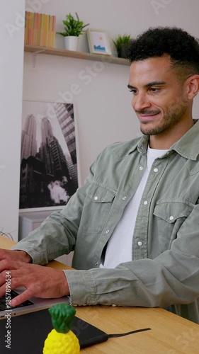 Vertical HD video of young adult Latin student working on laptop computer at home. Millennial African American creative man typing on computer sitting at home office desk. Business concept