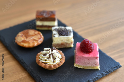 Plate of petit fours on wooden background
