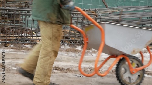 A construction worker drives a wheelbarrow on a construction site