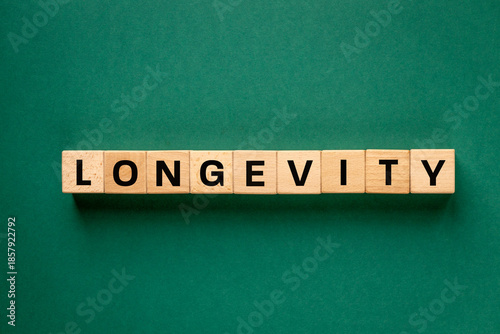 The word Longevity written on wooden blocks. The concept of longevity. Eating habits, positive attitude, social relationships, and physical activity. Beautiful dark green background