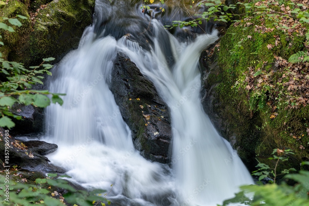 Fototapeta premium Long exposure of a waterfall on the East Lyn river flowing through the woods at Watersmeet in Exmoor National Park