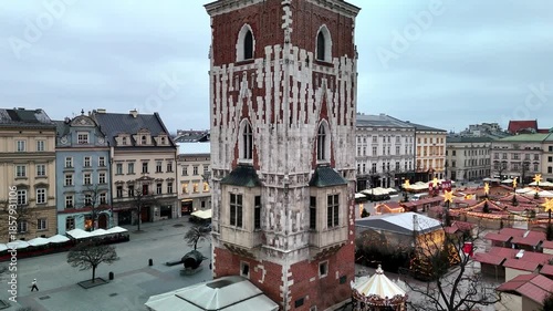 Cinematic drone shot rising past the historic Town Hall Tower over Krakow's empty Rynek Główny (Main Market Square) during a peaceful winter sunrise.