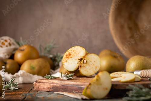 A rustic still life with sliced russet apples sprinkled with cinnamon on a wooden cutting board, evoking a cozy, autumnal mood
