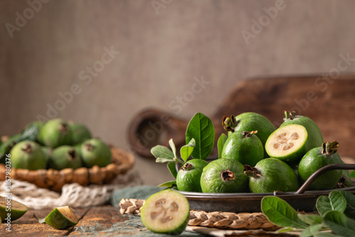 A rustic still life with ripe pineapple guavas, some cut open to reveal the fleshy pulp, on a small plate and in a basket