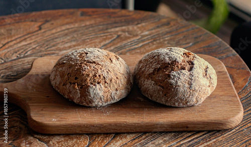 Принти на полотні Description
Two freshly baked artisan bread rolls with rustic crust on a wooden cutting board
