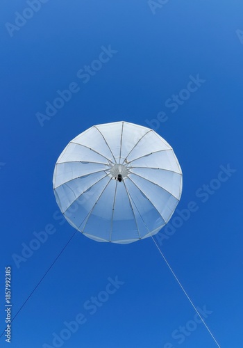 White Tethered Balloon Ascending in a Clear Blue Sky