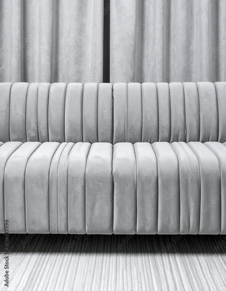 Obraz premium Elegant Gray Sofa with Vertical Pleats Against a Striped Wall.