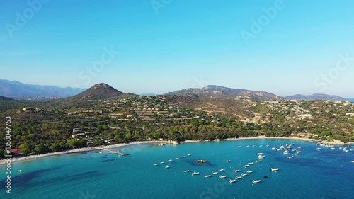 Scenic aerial view of Plage de Santa Giulia with turquoise waters, anchored boats, and lush green hills in Corsica, France.
