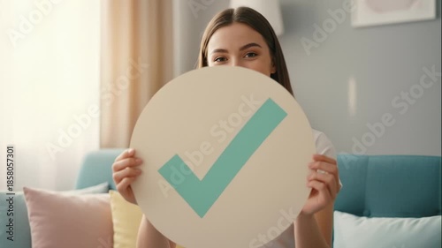 Woman Holding Check Mark Symbol in Living Room for Approval Concept