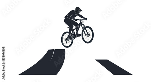 Mountain biker performing a jump on a downhill bike silhouette style.
