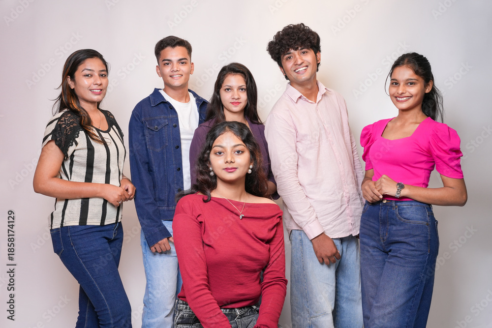 Obraz premium Group of young indian gen z friends standing together on a white background looking at camera.