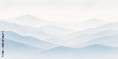 A majestic mountain landscape with clouds reveals a snow-covered peak rising above a misty forest valley during a blue morning sunrise where light breaks through the horizon fog