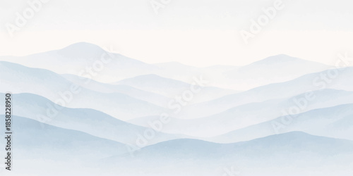 A misty mountain landscape with clouds and fog veiling the peaks over a snowy forest valley at sunset under a blue morning sky