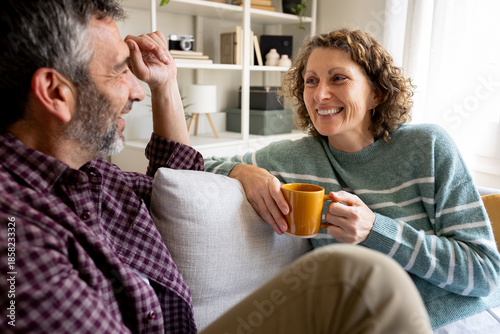 Happy mature couple relaxing on sofa talking and smiling