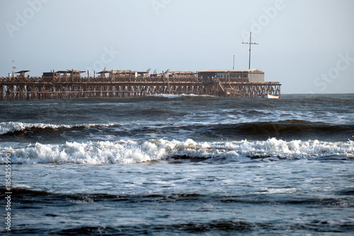 Tableau sur toile Old wooden pier in pimentel, peru, extending into the choppy pacific ocean with