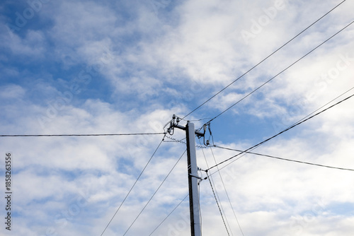 Utility pole with power lines against cloudy sky in daylight
