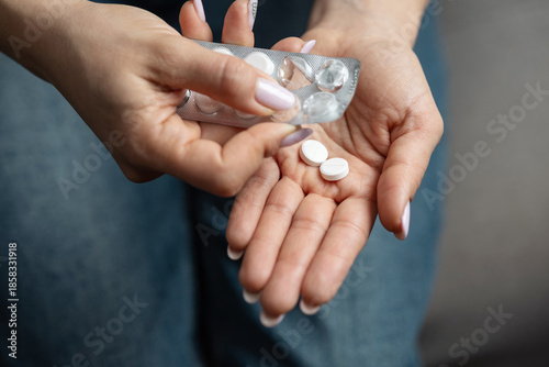 Quadro em tela Close-up of female hands taking pills from blister pack with white round scored