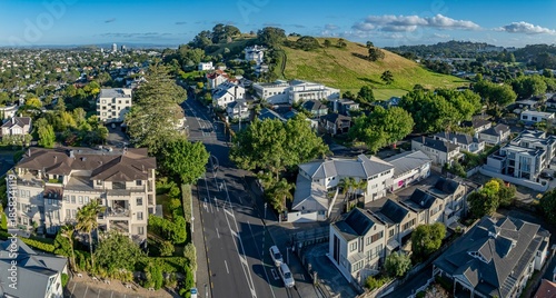 Aerial view of Mount Hobson in Remuera, Auckland, New Zealand. The photo shows residential buildings, a road with a car, and the volcanic peak of One Tree Hill.