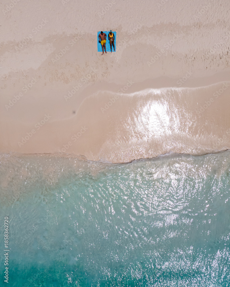 Fototapeta premium Visitors relax on soft white sands of Klein Curacao, enjoying the crystal-clear waters and warm sunshine. A perfect setting for a tropical holiday filled with bliss and tranquility.