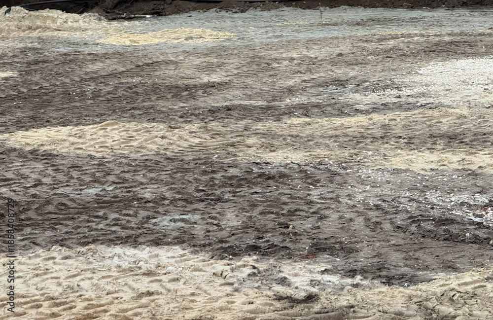 Fototapeta premium Workers are clearing muddy ground after recent rain at a construction site