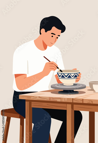 Young man paints intricate patterns on a handmade ceramic bowl with a brush