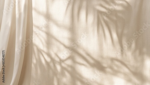 Soft sunlight shadows of tropical palm leaves cast on a neutral curtain creating a minimalist background for design projects